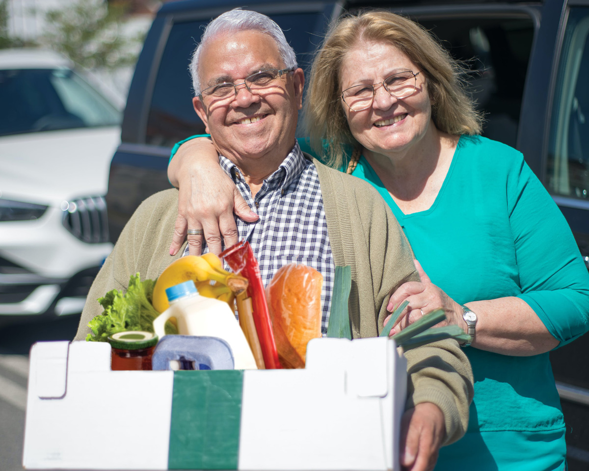a couple holding a box of groceries
